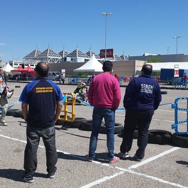 Varias personas observan una competición de karts en un circuito al aire libre.